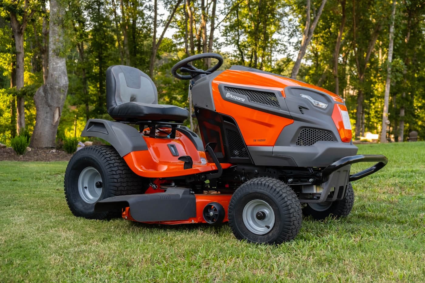 An orange riding lawn mower parked on a shaded green lawn