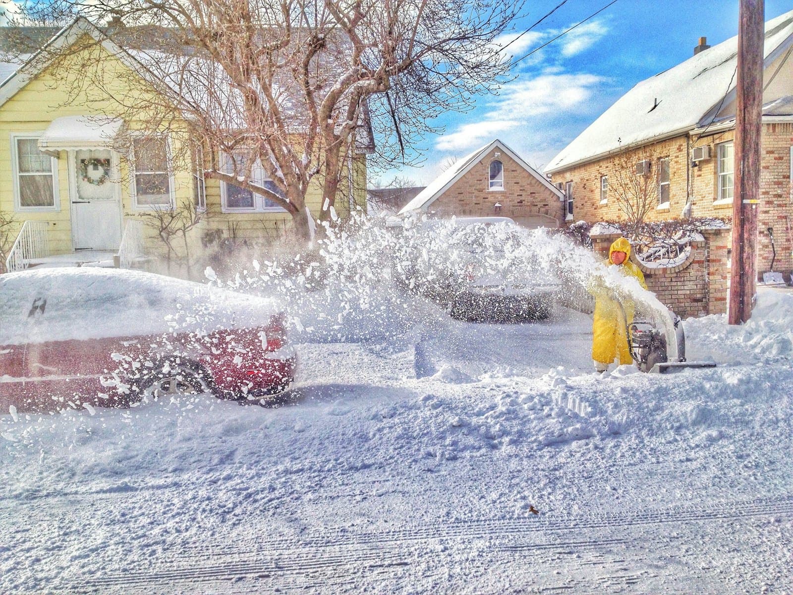 Someone clearing a driveway with a two-stage snow blower after a heavy Ohio snowfall